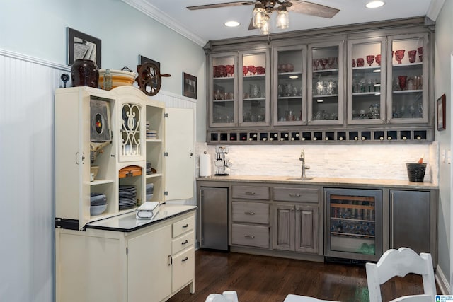 bar with wine cooler, sink, ornamental molding, backsplash, and dark wood-type flooring