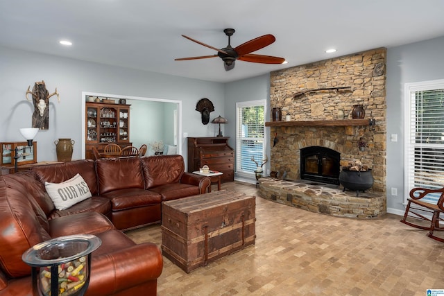 living room with a stone fireplace and ceiling fan