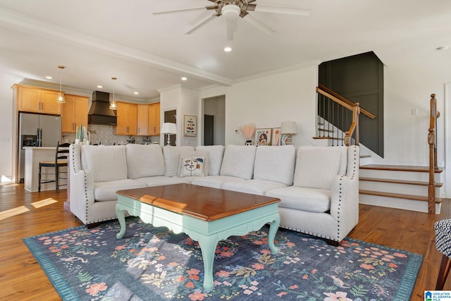 living room featuring wood-type flooring, ornamental molding, and ceiling fan