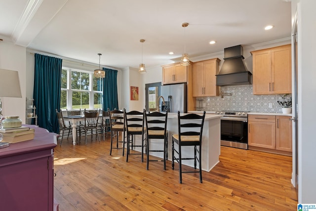 kitchen with hanging light fixtures, light hardwood / wood-style flooring, appliances with stainless steel finishes, custom range hood, and light brown cabinetry