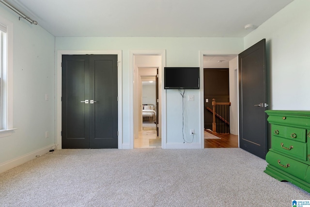 unfurnished bedroom with light carpet and a closet