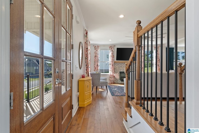 entrance foyer with light hardwood / wood-style flooring, crown molding, and a fireplace