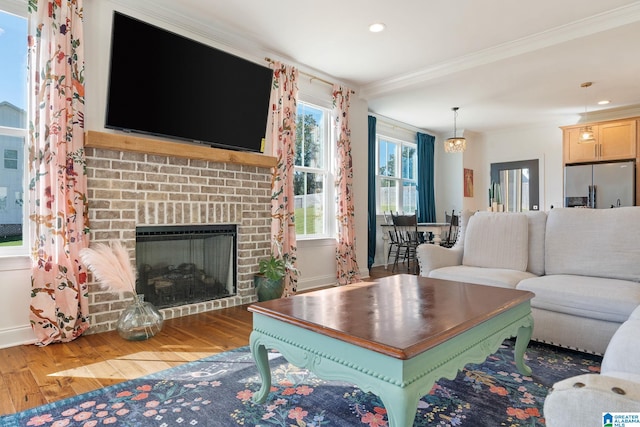 living room with ornamental molding, a brick fireplace, and wood-type flooring