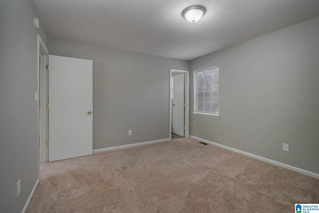 unfurnished room with light colored carpet and a textured ceiling