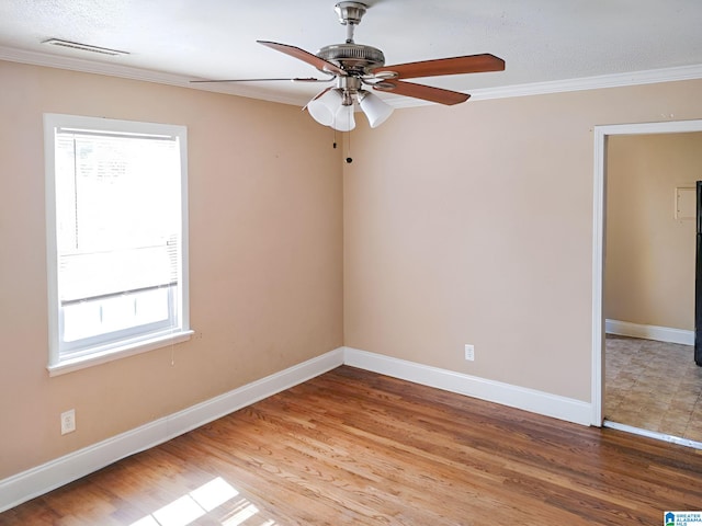 empty room featuring wood-type flooring, ceiling fan, ornamental molding, and a healthy amount of sunlight