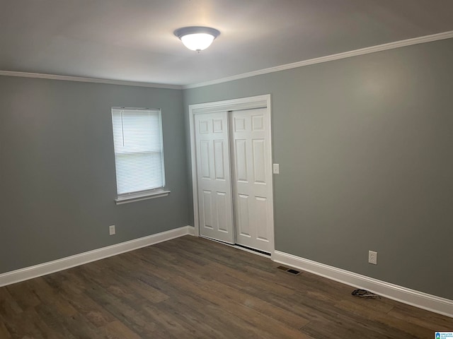 unfurnished bedroom with crown molding, a closet, and dark hardwood / wood-style floors