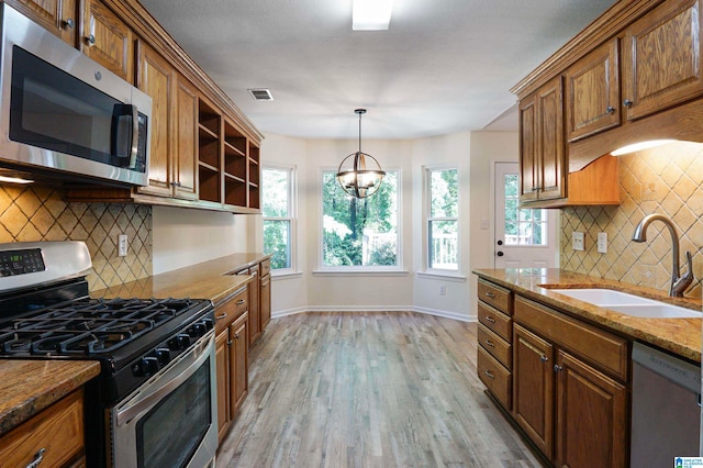 kitchen with light hardwood / wood-style flooring, appliances with stainless steel finishes, sink, and decorative backsplash