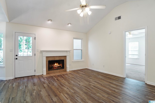 unfurnished living room with ceiling fan, lofted ceiling, a tile fireplace, and dark hardwood / wood-style floors