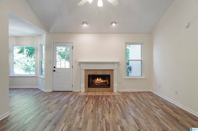 unfurnished living room with light hardwood / wood-style floors, a tiled fireplace, and plenty of natural light