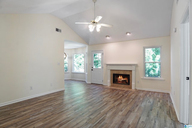 unfurnished living room featuring vaulted ceiling, a tiled fireplace, dark hardwood / wood-style floors, and plenty of natural light