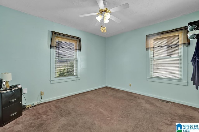 spare room with ceiling fan, plenty of natural light, and carpet floors