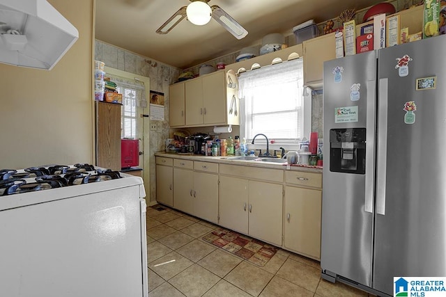 kitchen featuring stainless steel fridge, gas range gas stove, sink, and cream cabinetry