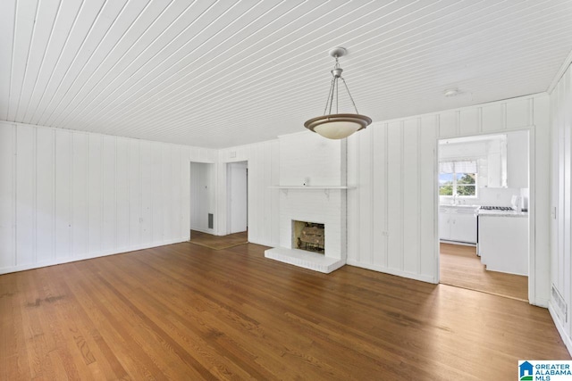 unfurnished living room with hardwood / wood-style floors and a brick fireplace