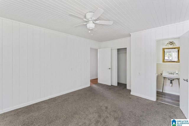 unfurnished bedroom with sink, ensuite bath, a closet, ceiling fan, and dark colored carpet