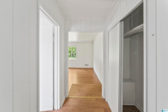 hall featuring light hardwood / wood-style floors and wooden walls