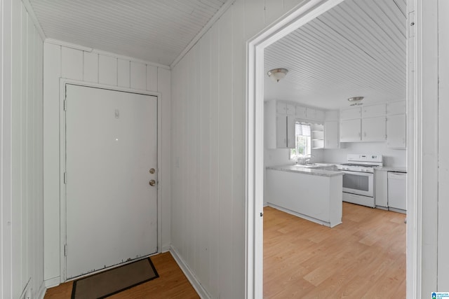 entryway featuring sink, light wood-type flooring, and wood walls