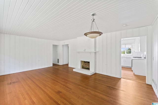 unfurnished living room with light hardwood / wood-style floors and a brick fireplace