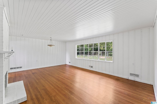 unfurnished living room with wooden walls, a brick fireplace, hardwood / wood-style flooring, and wood ceiling