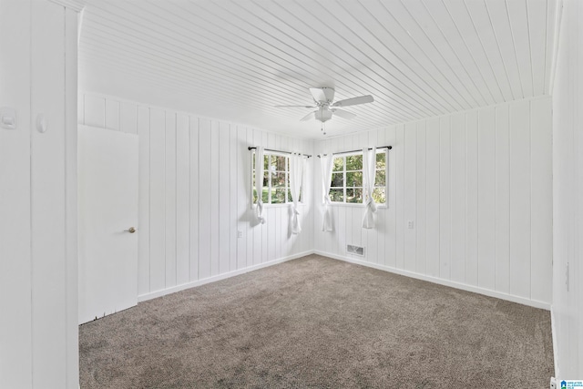 spare room with wood ceiling, wooden walls, carpet, and ceiling fan