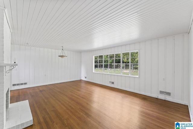 unfurnished living room with a fireplace, wooden ceiling, dark hardwood / wood-style floors, and wood walls