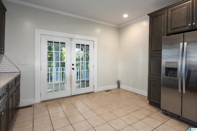 kitchen with dark brown cabinetry, stainless steel fridge, tasteful backsplash, french doors, and light stone countertops