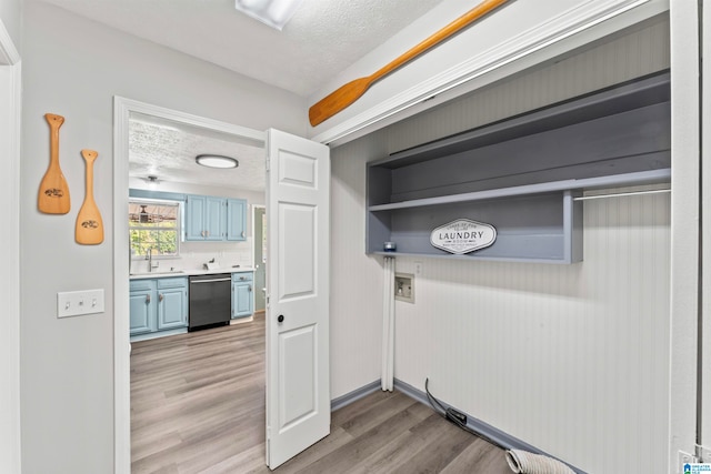 laundry room featuring sink, hookup for a washing machine, light hardwood / wood-style flooring, and a textured ceiling