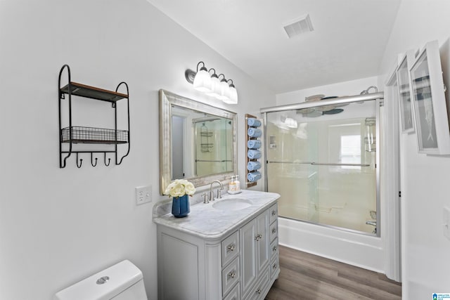 full bathroom featuring bath / shower combo with glass door, wood-type flooring, vanity, and toilet