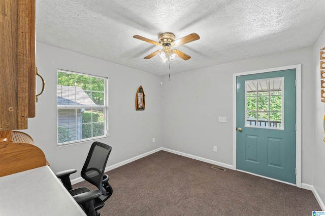 office featuring dark carpet, a textured ceiling, ceiling fan, and a wealth of natural light