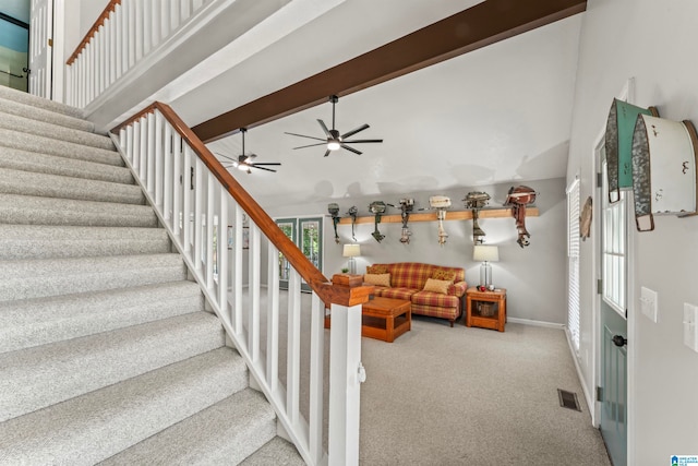 staircase with a towering ceiling, beam ceiling, and carpet flooring