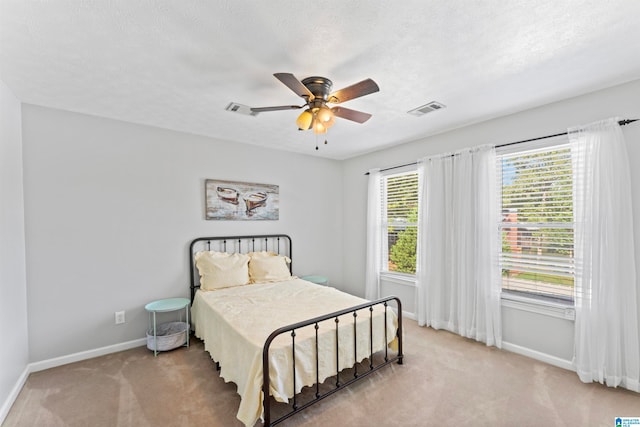 bedroom with light colored carpet, a textured ceiling, and ceiling fan