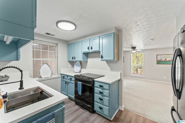 kitchen featuring light hardwood / wood-style floors, fridge, blue cabinetry, black range with electric stovetop, and sink