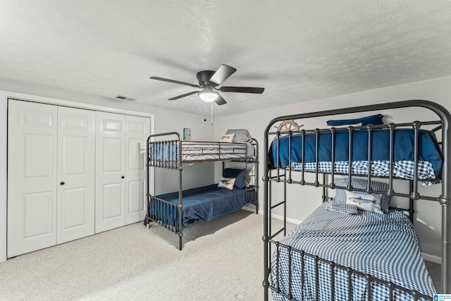 carpeted bedroom with a closet, a textured ceiling, and ceiling fan