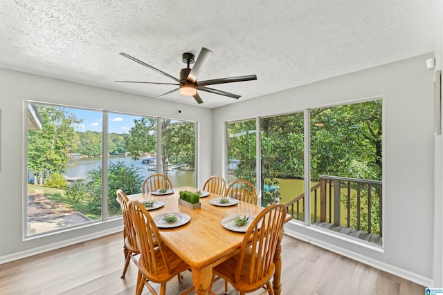 sunroom / solarium featuring a water view, ceiling fan, and a healthy amount of sunlight