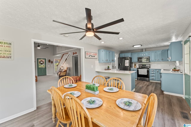 dining room with ceiling fan, sink, dark hardwood / wood-style floors, and a textured ceiling