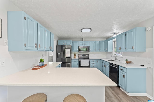 kitchen featuring sink, kitchen peninsula, light hardwood / wood-style flooring, appliances with stainless steel finishes, and a breakfast bar area