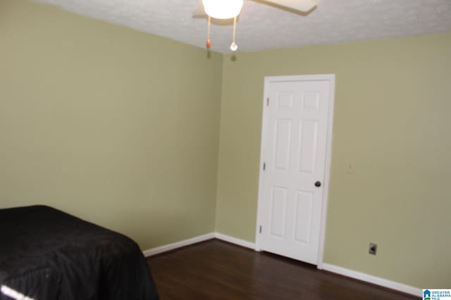 bedroom with dark hardwood / wood-style flooring, a textured ceiling, and ceiling fan