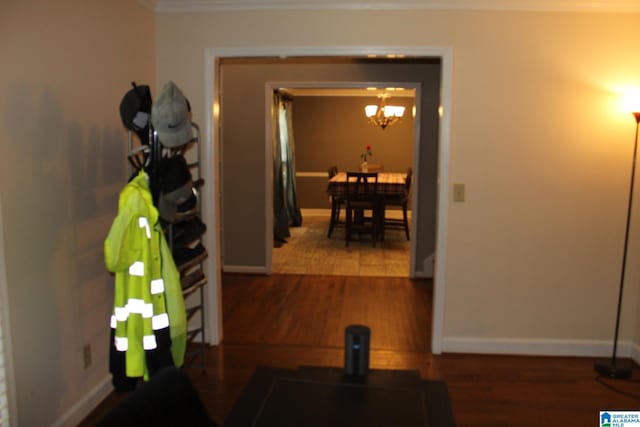 corridor with ornamental molding, hardwood / wood-style floors, and a chandelier