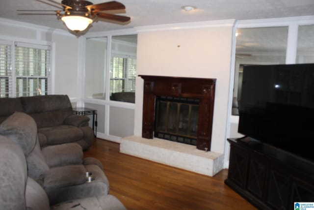 living room featuring a fireplace, crown molding, hardwood / wood-style flooring, and ceiling fan