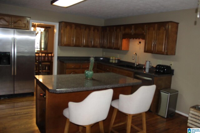 kitchen with dark wood-type flooring, stainless steel fridge, sink, and a center island