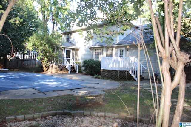 rear view of house with a covered pool and a patio