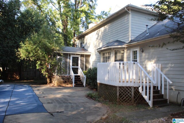 back of house with a wooden deck, a sunroom, and a patio area