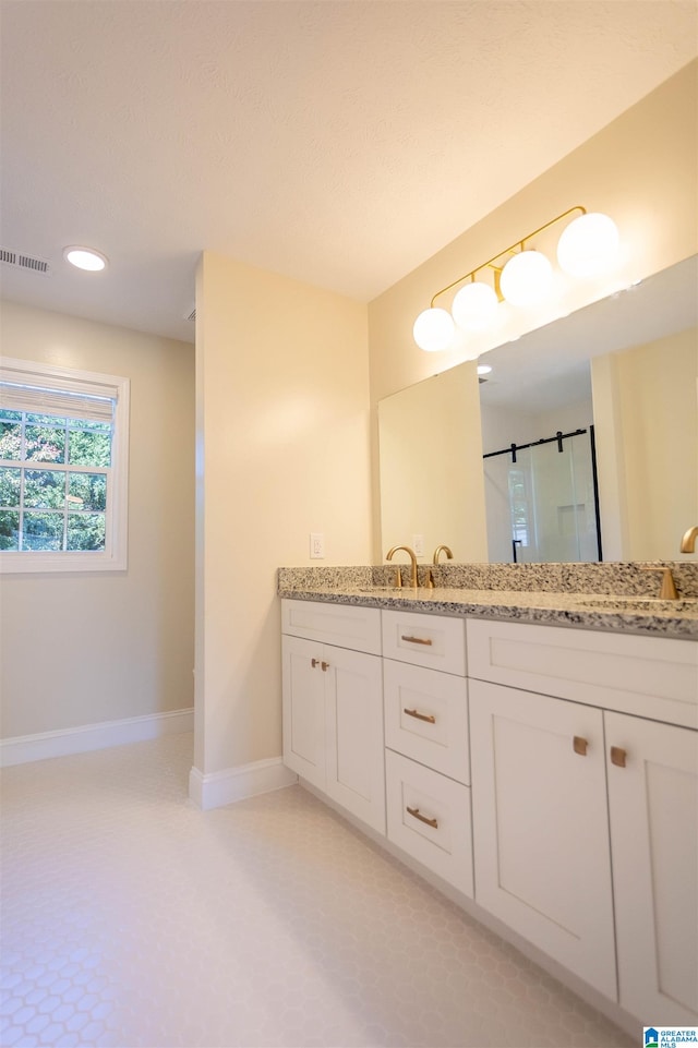 bathroom featuring a shower with door and vanity