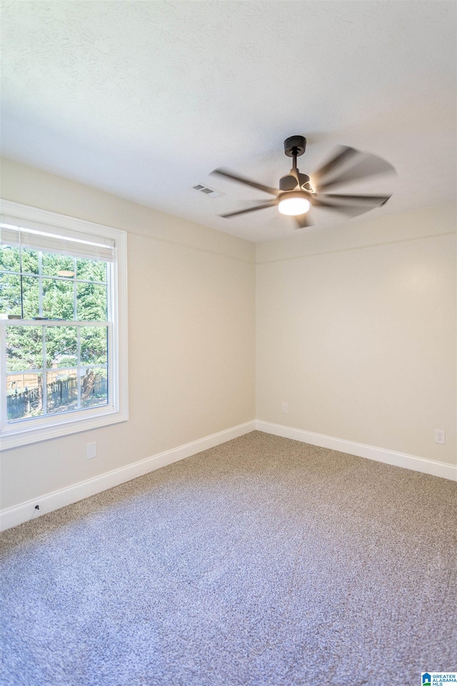 carpeted spare room featuring ceiling fan and a textured ceiling