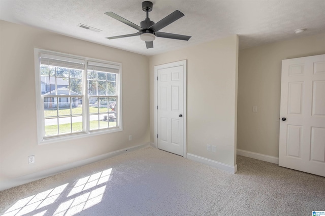 unfurnished bedroom with ceiling fan, a textured ceiling, and light carpet