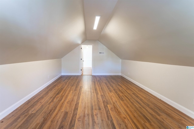 additional living space with vaulted ceiling and dark hardwood / wood-style flooring