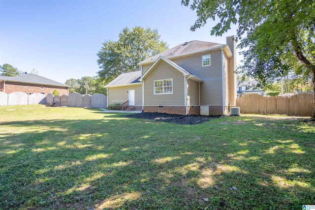 rear view of property with central AC and a lawn