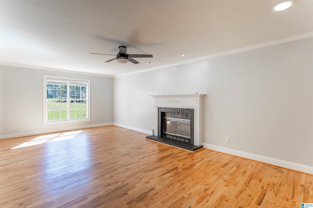 unfurnished living room with ceiling fan, light wood-type flooring, a fireplace, and ornamental molding