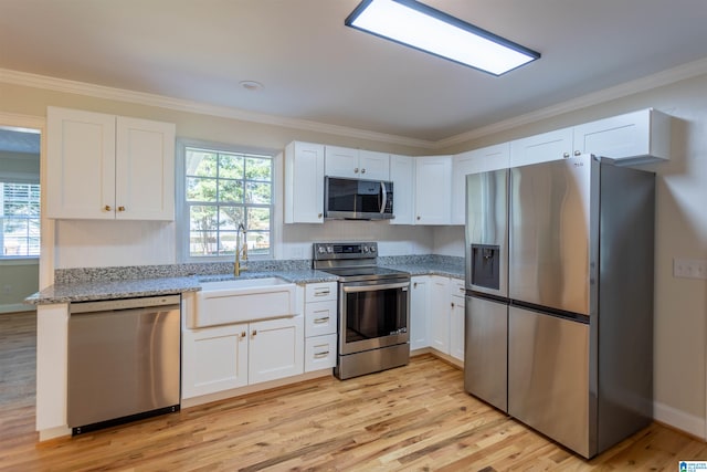 kitchen with white cabinets, appliances with stainless steel finishes, and light hardwood / wood-style flooring