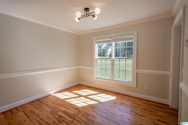 unfurnished room featuring ornamental molding, plenty of natural light, an inviting chandelier, and light hardwood / wood-style flooring