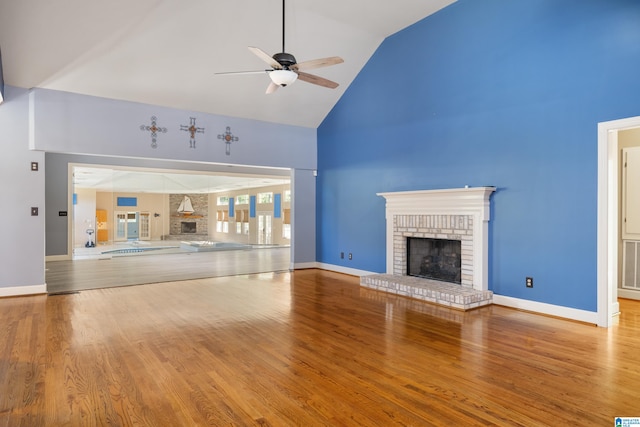 unfurnished living room featuring high vaulted ceiling, wood-type flooring, and a brick fireplace